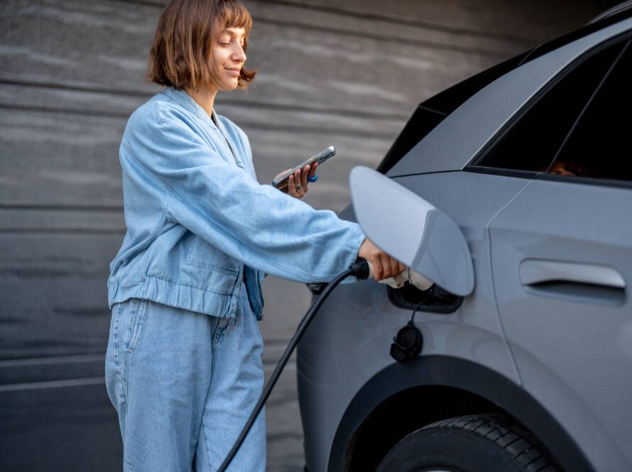 Beschrijving: Een vrouw laadt haar elektrische auto op met een laadpaal.