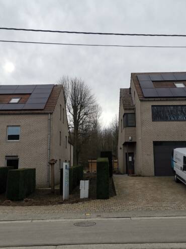 Twee huizen met zonnepanelen op hun dak.