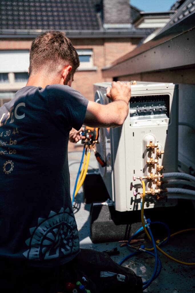 Een technicus werkt aan de bedrading en meters van een buitenairco op een dak.