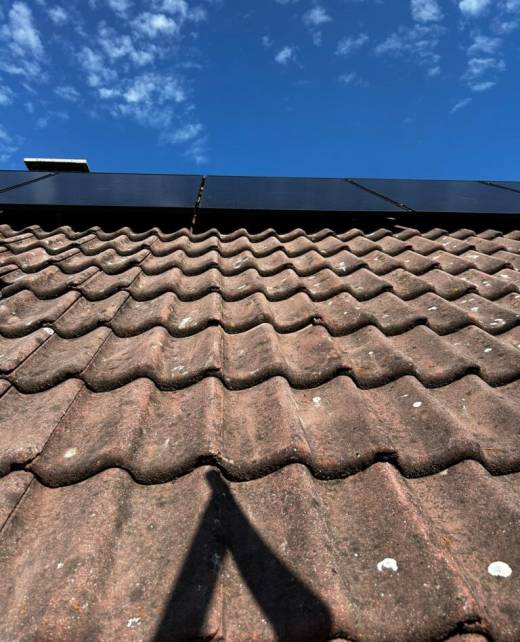 De schaduw van een zonnepaneel op een dak.